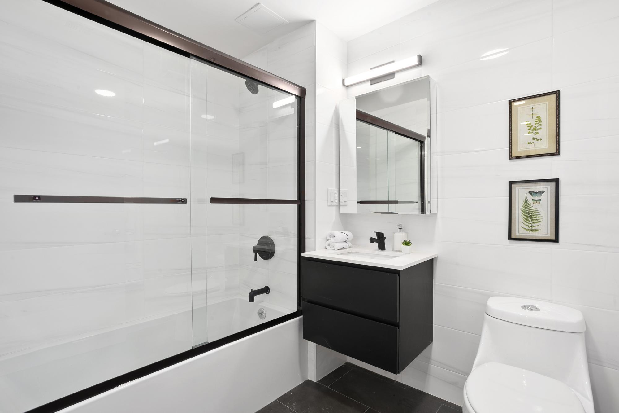 Modern Bathroom with White Tile, Toilet, Sink Counter and Tub, Dark Sink and Tub Fixtures, Floating Sink Drawer Vanity and Dark Flooring